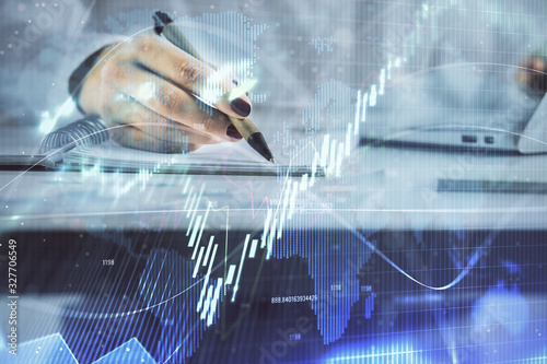 Double exposure of woman's hands making notes with forex graph hologram. Concept technical analysis.