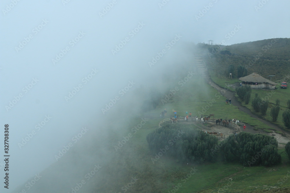 The fog is coming in from the edge of a cliff in de andes near quito, slowly covering the horse stable, path and house The fog is coming in from the edge of a cliff in de andes near quito, slowly covering the horse stable, path and house