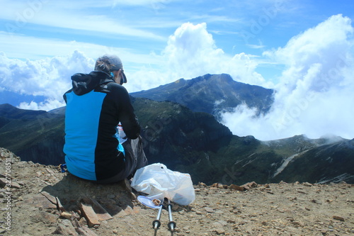 A hiker enjoying the view with some food after reaching the top of the mountain Rucu Pinchincha in the Andes of Ecuador photo