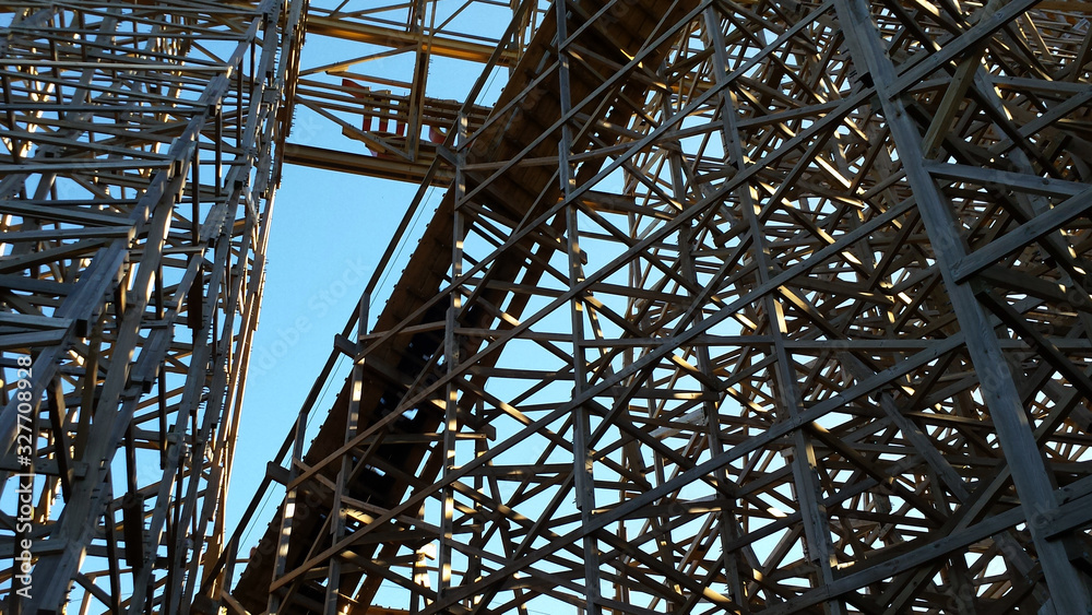 The wooden frame or structure of a rollecoaster from below showing the intricate structure