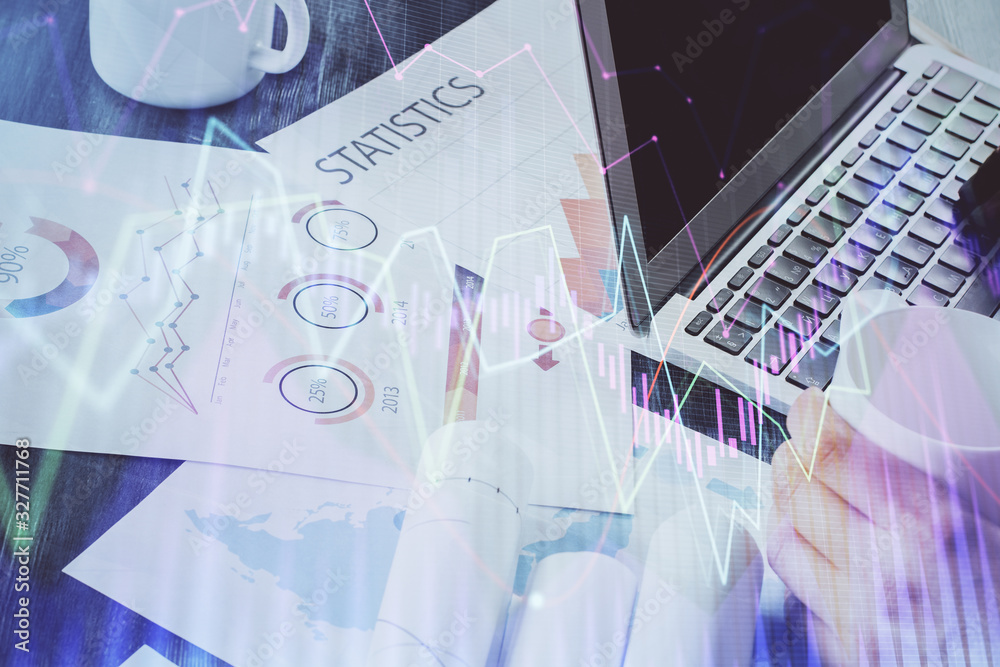 Double exposure of stock graph with businessman typing on computer in office on background. Concept of hard work.