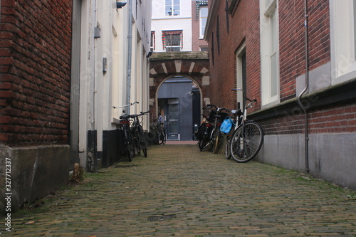 Fototapeta Naklejka Na Ścianę i Meble -  Small alley looking old, paved with pebbles and surrounded by brick walls with bicycles parked at both sides