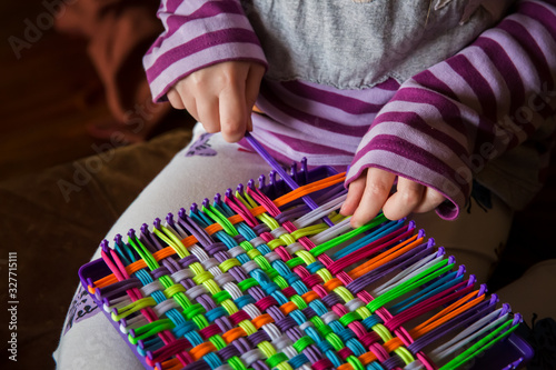 Child weaving potholder on plastic loom photo