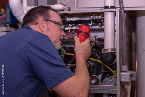 HVAC Tech Looking Over A Gas Furnace Blue Shirt 