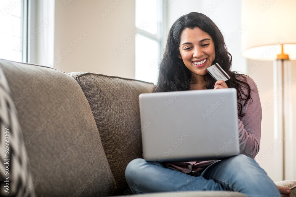 Naklejka premium Young Hispanic woman shopping online at home.