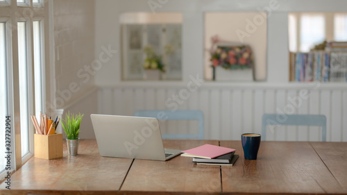 Close up view of comfortable workplace with laptop, stationery and coffee cup on wooden desk