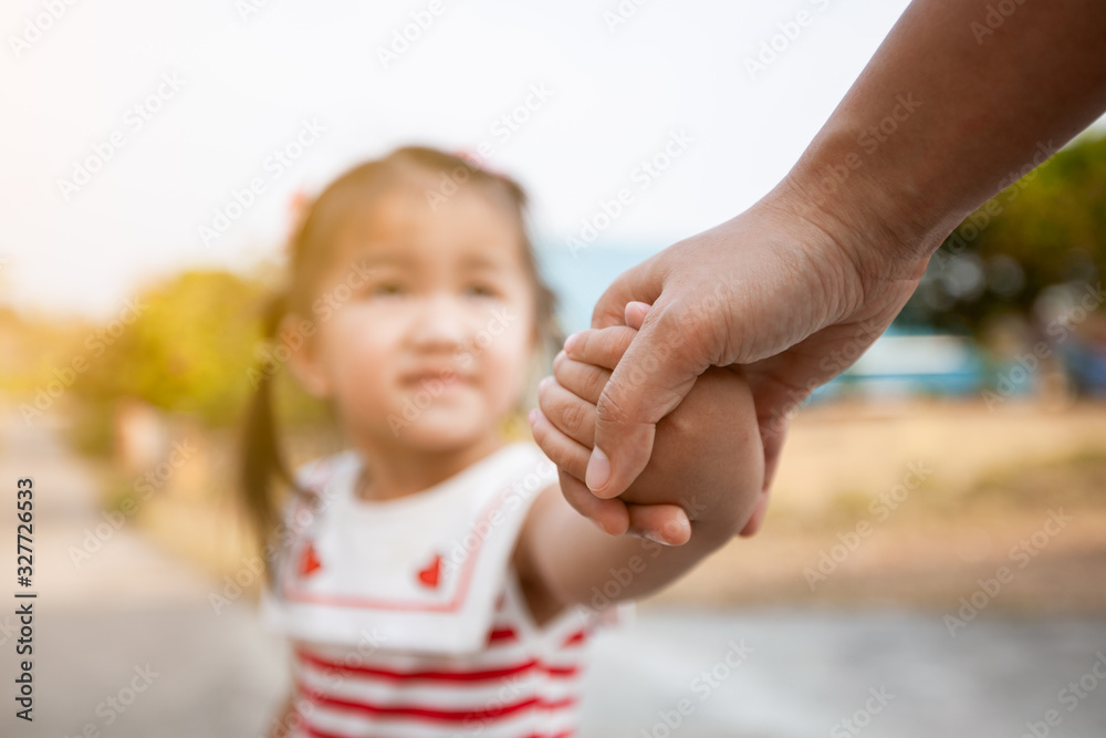 Parent and asian child girl holding hand together with love and care Parent and asian child girl holding hand together with love and care
