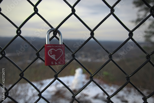 One single padlock with a heart scratched carved into it with initials and the a love quote attached to a fence surrounding Flag Rock at Norton Virginia