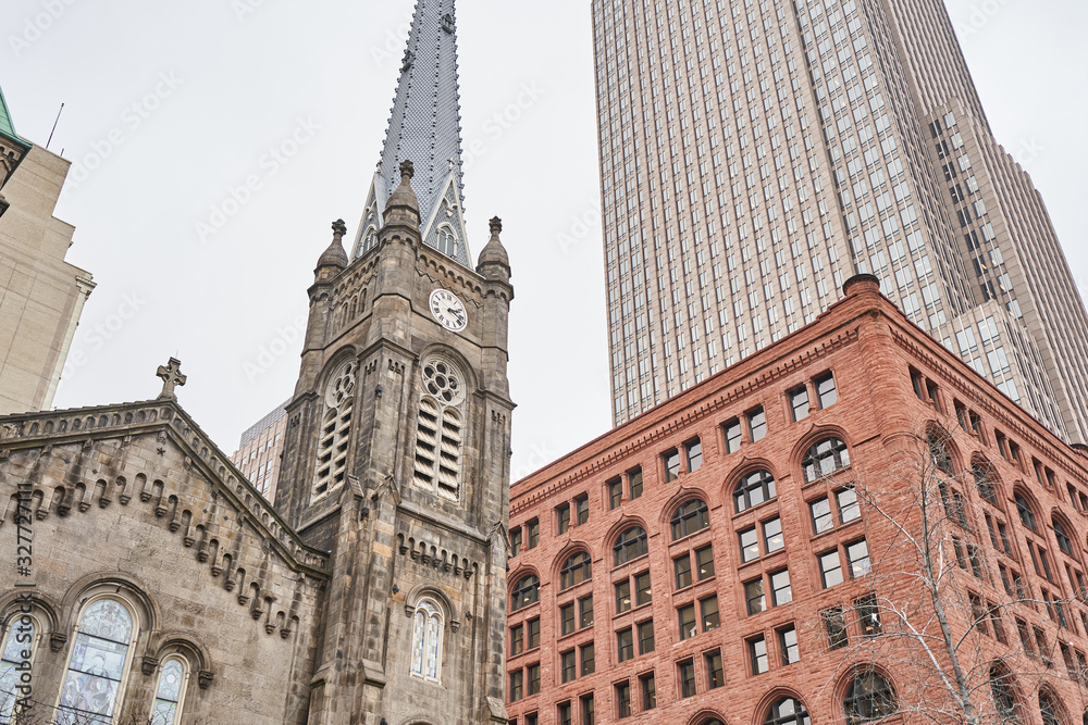 The Old Stone Church in Cleveland Ohio, dwarfed by the nearby surrounding buildings and skyscrapers. It stands in the shadow of the Key Tower. The Romanesque architecture contrasts nearby buildings. The Old Stone Church in Cleveland Ohio, dwarfed by the nearby surrounding buildings and skyscrapers. It stands in the shadow of the Key Tower. The Romanesque architecture contrasts nearby buildings.