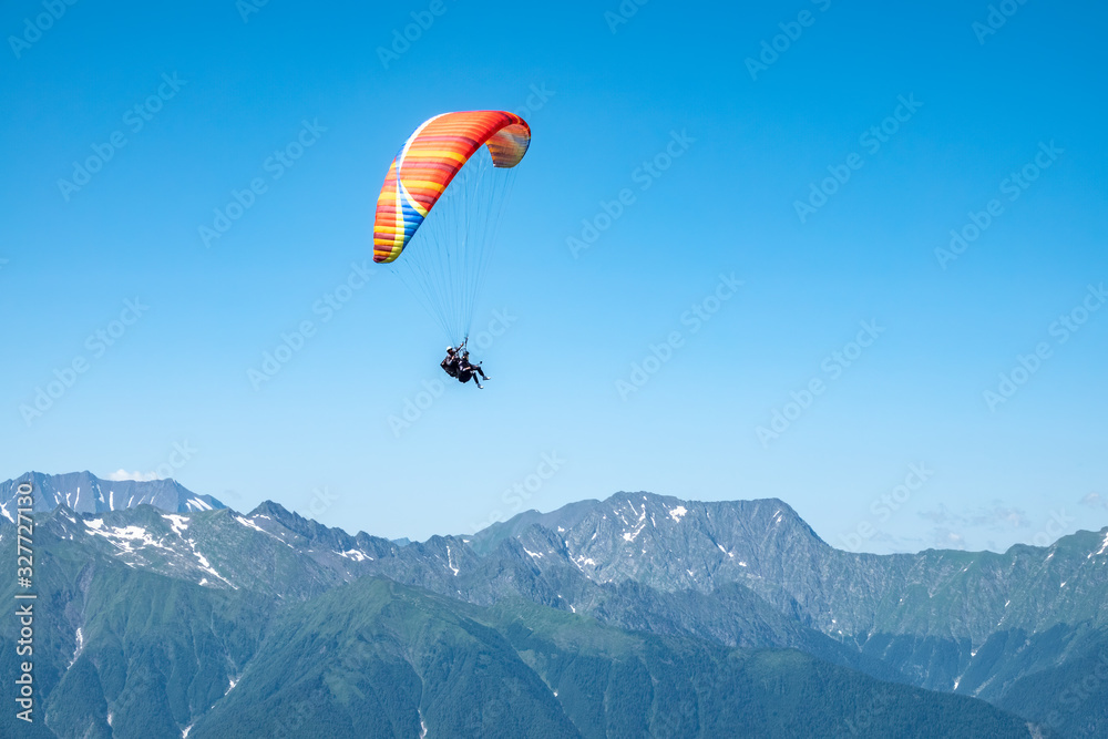 Red paraglider in blue clear sky over the Green Mountain Red paraglider in blue clear sky over the Green Mountain