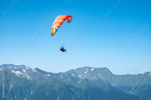 Red paraglider in blue clear sky over the Green Mountain