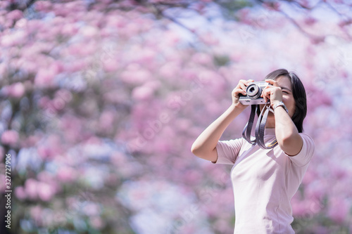 Happy asian woman tourist in spring blossom park walking and take a photo leisure activity in holiday trip