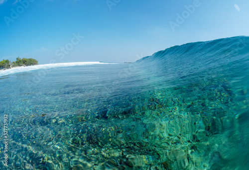 Crystal clear ocean wave breaks over the reef