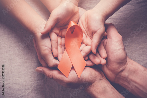 Adult and child hands holding orange Ribbons,  Leukemia cancer and Multiple sclerosis, COPD and ADHD awareness, world kidney day