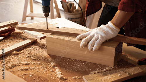 Tableau sur toile Carpenter using drill to screwing pieces of board at site.