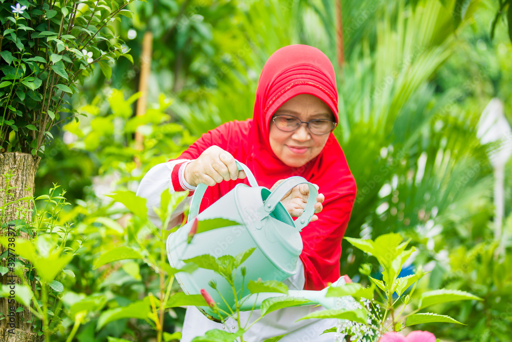Senior muslim woman gardening with a watering can