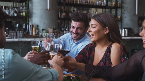 Group of friends meeting in restaurant celebrating and making a toast - shot in slow motion