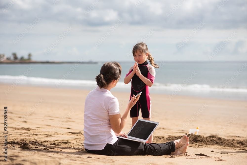Daughter begs young mother to play with her at the beach