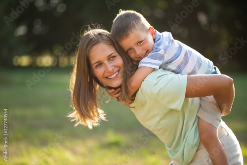 Fotografie Smiling cute kid enjoying piggyback ride outdoors