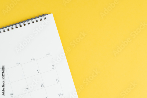 Calendar with blank copy space to put month and year on solid yellow background, flat lay or top view with calendar on the left and text space on the right
