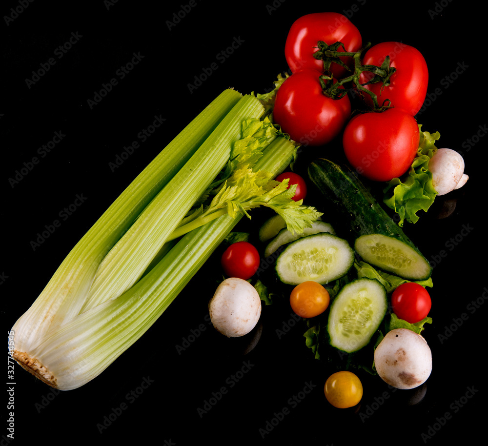 Fresh vegetables, cucumber, mushrooms, onions, cherry tomatoes, lettuce on a black background, close-up, space for text Fresh vegetables, cucumber, mushrooms, onions, cherry tomatoes, lettuce on a black background, close-up, space for text