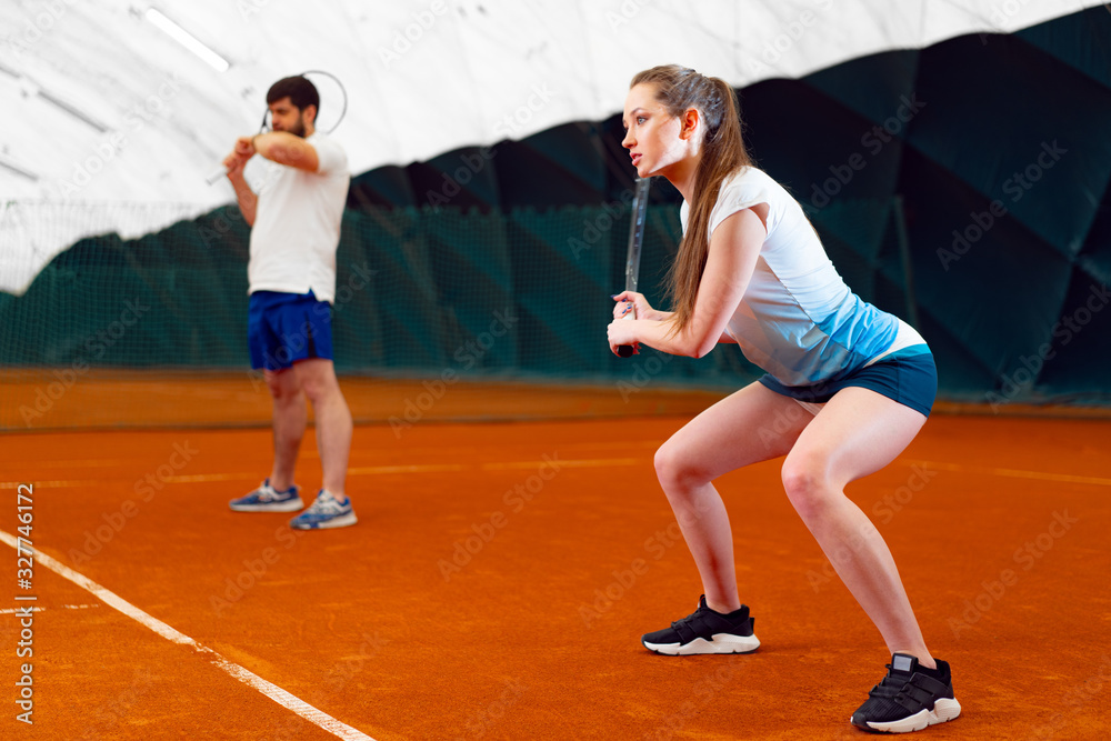 Pair of tennis players, man and woman waiting for service at indoor court