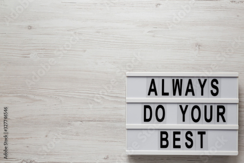'Always do your best' words on a lightbox on a white wooden surface, top view. Overhead, from above, flat lay. Space for text.