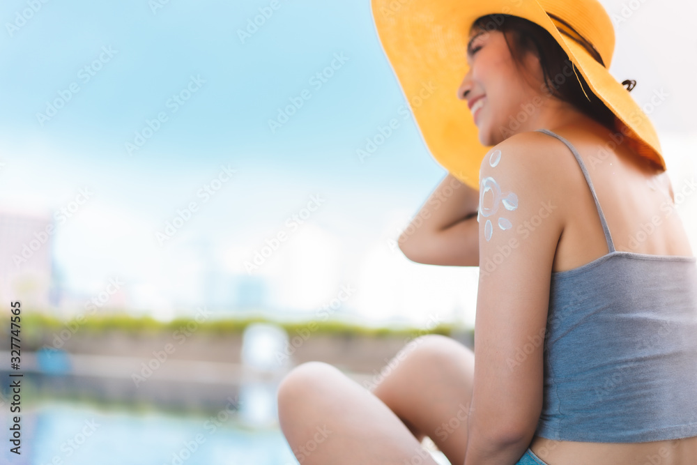 Enjoying vacation. Back view of slim young woman in swimming pool.Young asian woman relaxing in swimming pool .Asian Woman hands applying sunscreen cream, woman using sunblock .