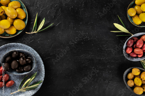 Olives, green, black and red, an assortment with leaves on a dark table with a place for text, a flat lay design template