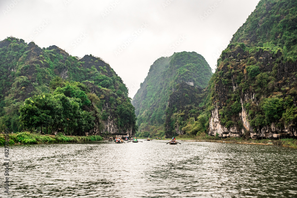 Tam Coc National Park - Tourists traveling in boats along the Ngo Dong River at Ninh Binh Province, Trang An landscape complex, Vietnam - Landscape formed by karst towers and rice fields
