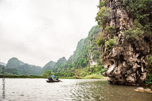 Tam Coc National Park - Tourists traveling in boats along the Ngo Dong River at Ninh Binh Province, Trang An landscape complex, Vietnam - Landscape formed by karst towers and rice fields