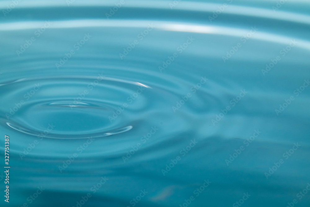 Closeup Water drop falling on the surface of the water and beautiful circular wave ripple, fresh natural mineral water drink water concept Closeup Water drop falling on the surface of the water and beautiful circular wave ripple, fresh natural mineral water drink water concept