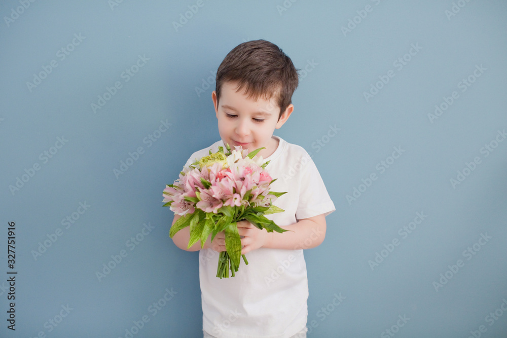 Little boy in white t-shirt holds bouquet of pink flowers