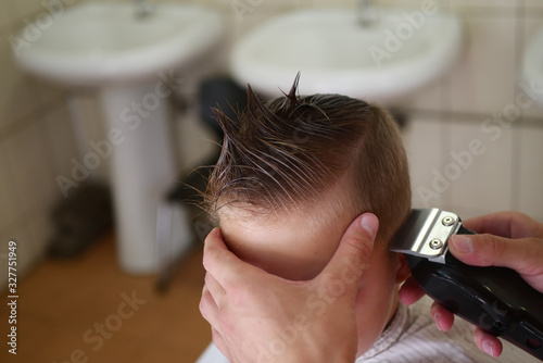 Hairdresser haircuts the boy with a typewriter. Boy haircut