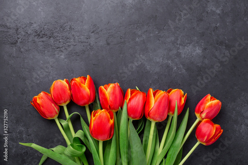 Bouquet of red tulips on a dark stone table. Spring background. Copy space for your congratulations