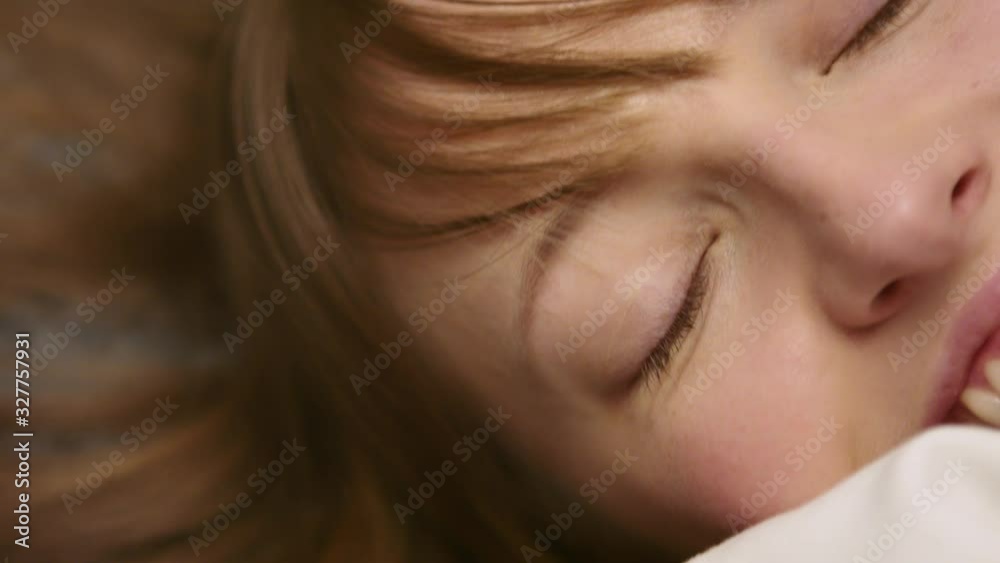 A lovely woman lying in bed hugging a soft white blanket smiling at the camera - closeup shot A lovely woman lying in bed hugging a soft white blanket smiling at the camera - closeup shot