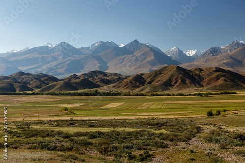 green pastures against the backdrop of snowy mountains near Lake Issyk-Kul, Kyrgyzstan.
