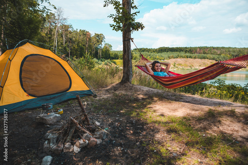 woman laying on hammock at camp near lake summer hiking concept