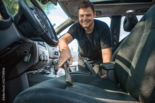 man cleaning inside car with vacuum cleaner