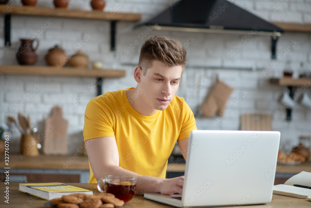Young fair-haired man in yellow tshirt looking involved Young fair-haired man in yellow tshirt looking involved