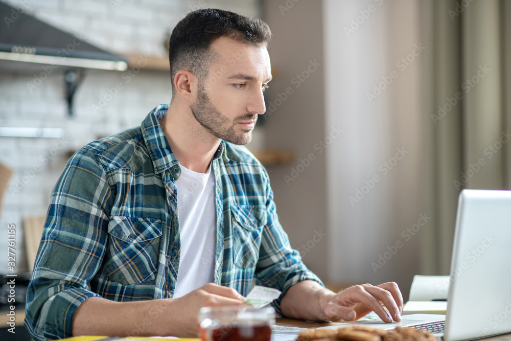 Young man in a checkered shirt working on a laptop Young man in a checkered shirt working on a laptop