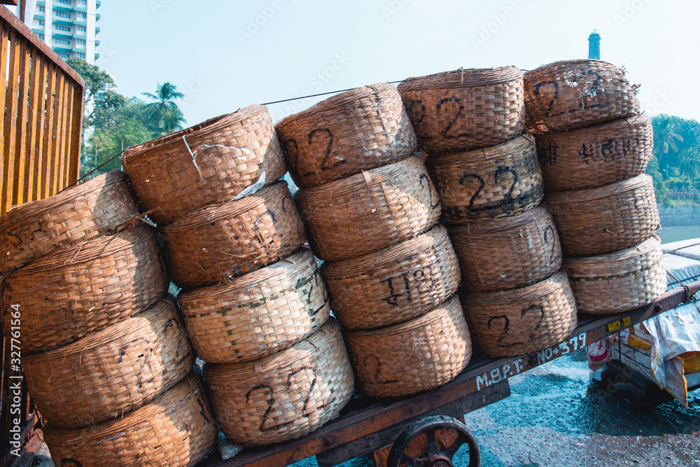 The famous Sassoon Docks Fish Market in Mumbai, India. Piles of round wicker containers marked with markers on a wheel barrow. The famous Sassoon Docks Fish Market in Mumbai, India. Piles of round wicker containers marked with markers on a wheel barrow.