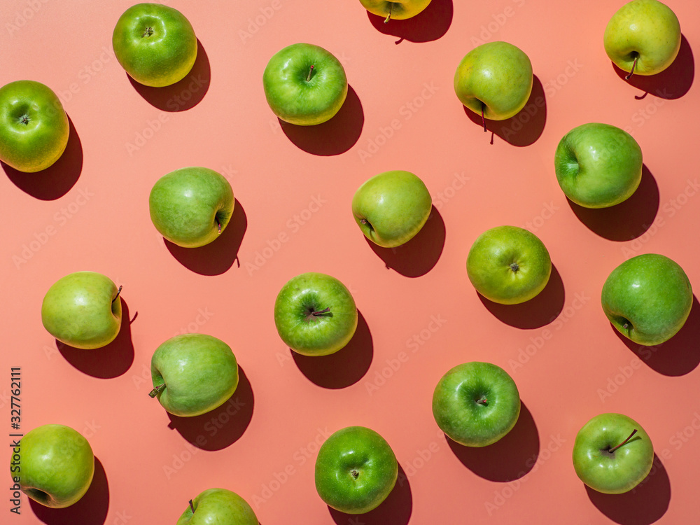 Green apples on orange or coral pink background pattern. Colorful fruit frame. Flat lay or top view, Hard light. Creative concept. Green apples on orange or coral pink background pattern. Colorful fruit frame. Flat lay or top view, Hard light. Creative concept.