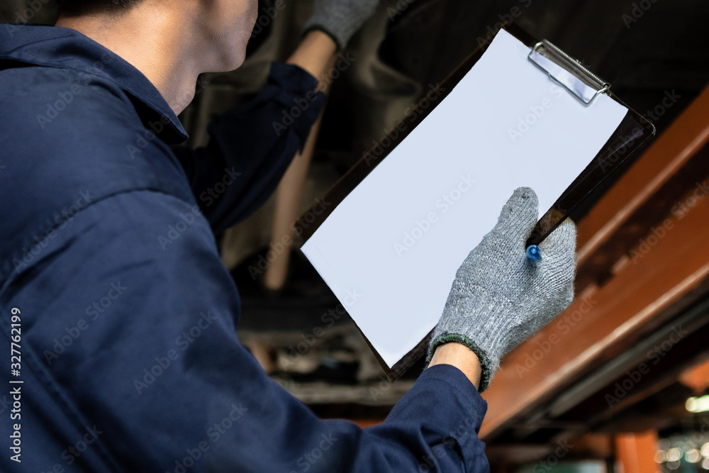 A mechanic service car in garage is check a list cars.