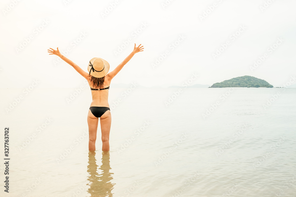 Beautiful woman in sunhat and bikini standing at the beach Beautiful woman in sunhat and bikini standing at the beach