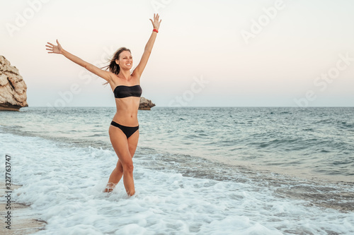 Young woman in black bikini on the beach in the evening