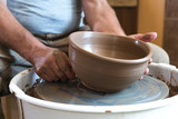 Potter working with clay on wheel.