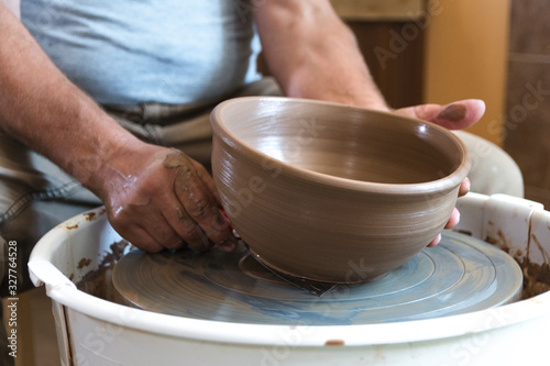 Potter working with clay on wheel.