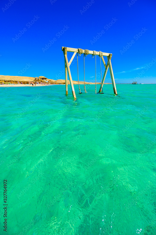 Swing in crystal clear azure water - Orange Bay Beach with white beach - paradise coastline of Giftun island, Mahmya, Hurghada, Red Sea, Egypt Swing in crystal clear azure water - Orange Bay Beach with white beach - paradise coastline of Giftun island, Mahmya, Hurghada, Red Sea, Egypt