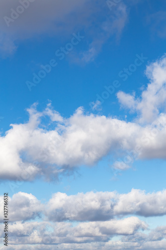 Snow-white fluffy clouds against the blue sky. Vertical.